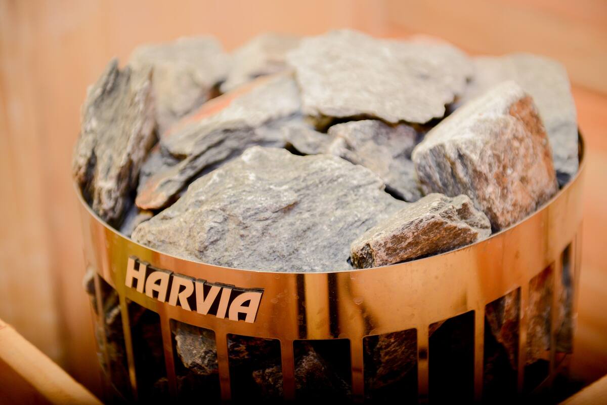 Un recipiente metálico con la palabra "HARVIA" grabado, lleno de piedras.