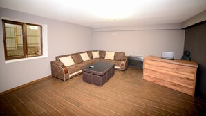 A living room with a sectional sofa, a wooden coffee table, a desk with a laptop, and a large window with curtains. - samta (Tsqaltubo)