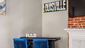 Eine Bar mit zwei blauen Samtstühlen, einer schwarzen Bar und einem Schild mit der Aufschrift 'LOUISVILLE'.