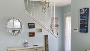 A living room with a staircase, a console table, a sofa, and a wall with decorative items. - Charming Family Friendly Townhome Walk to Beach, Near AC Fun, Pet Friendly (Brigantine)