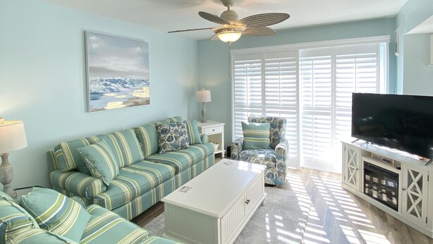 A living room with a sofa set, a coffee table, a television on a cabinet, and a ceiling fan. - Charming Family Friendly Townhome Walk to Beach, Near AC Fun, Pet Friendly (Brigantine)