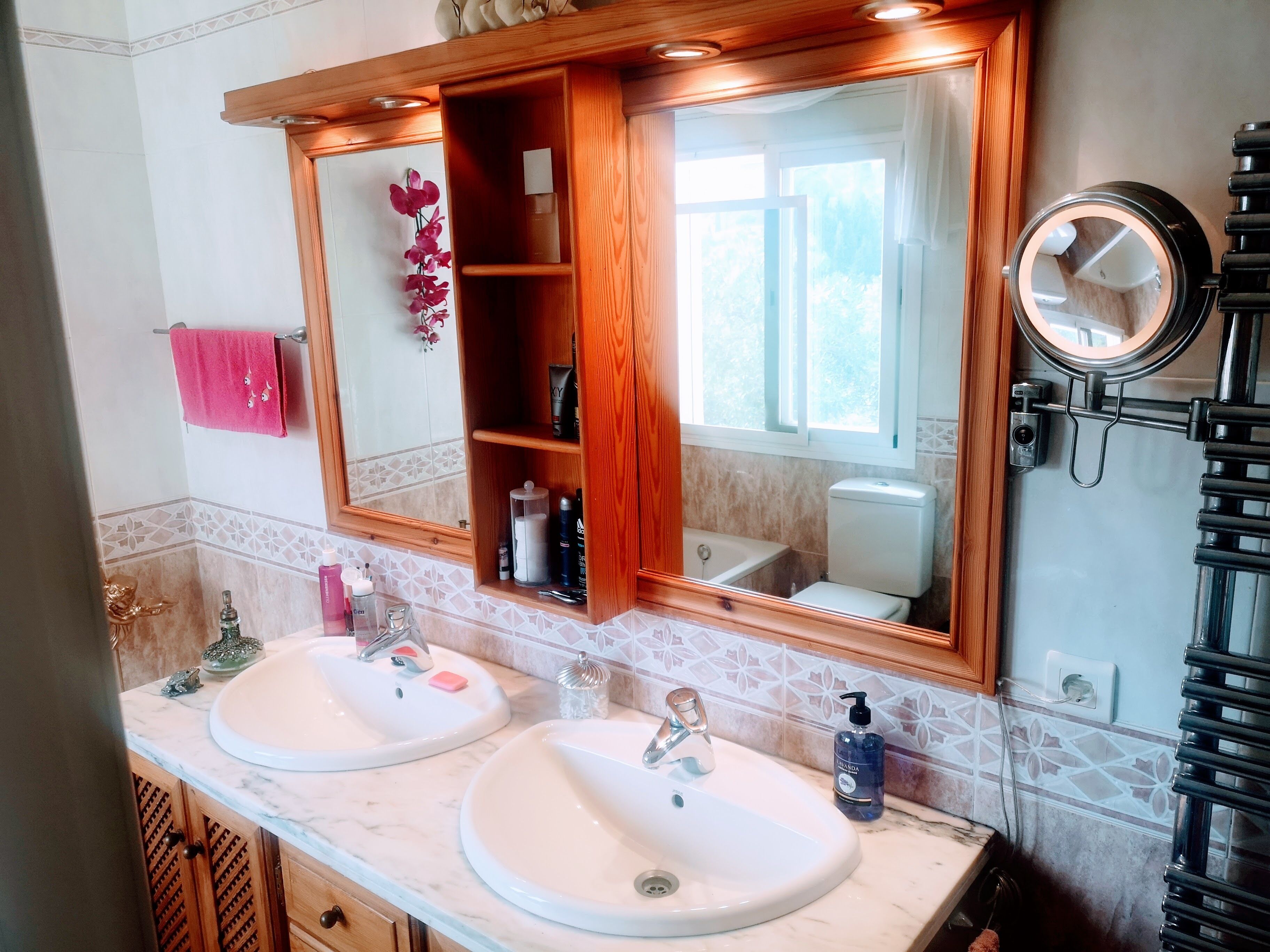Une salle de bain avec deux lavabos, un miroir et des toilettes.