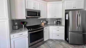 A modern kitchen with white cabinets, stainless steel appliances, and a granite countertop. - Salt Water Pool & Spa Escape (North Port)