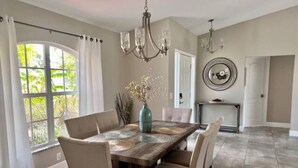 A dining area with a wooden table, beige chairs, and a vase with flowers. - Salt Water Pool & Spa Escape (North Port)