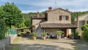 A stone house with a tiled roof, a covered patio with outdoor furniture, and potted plants. -  Il Mulino Di Vogognano by Geco Vacation Rentals (Subbiano)