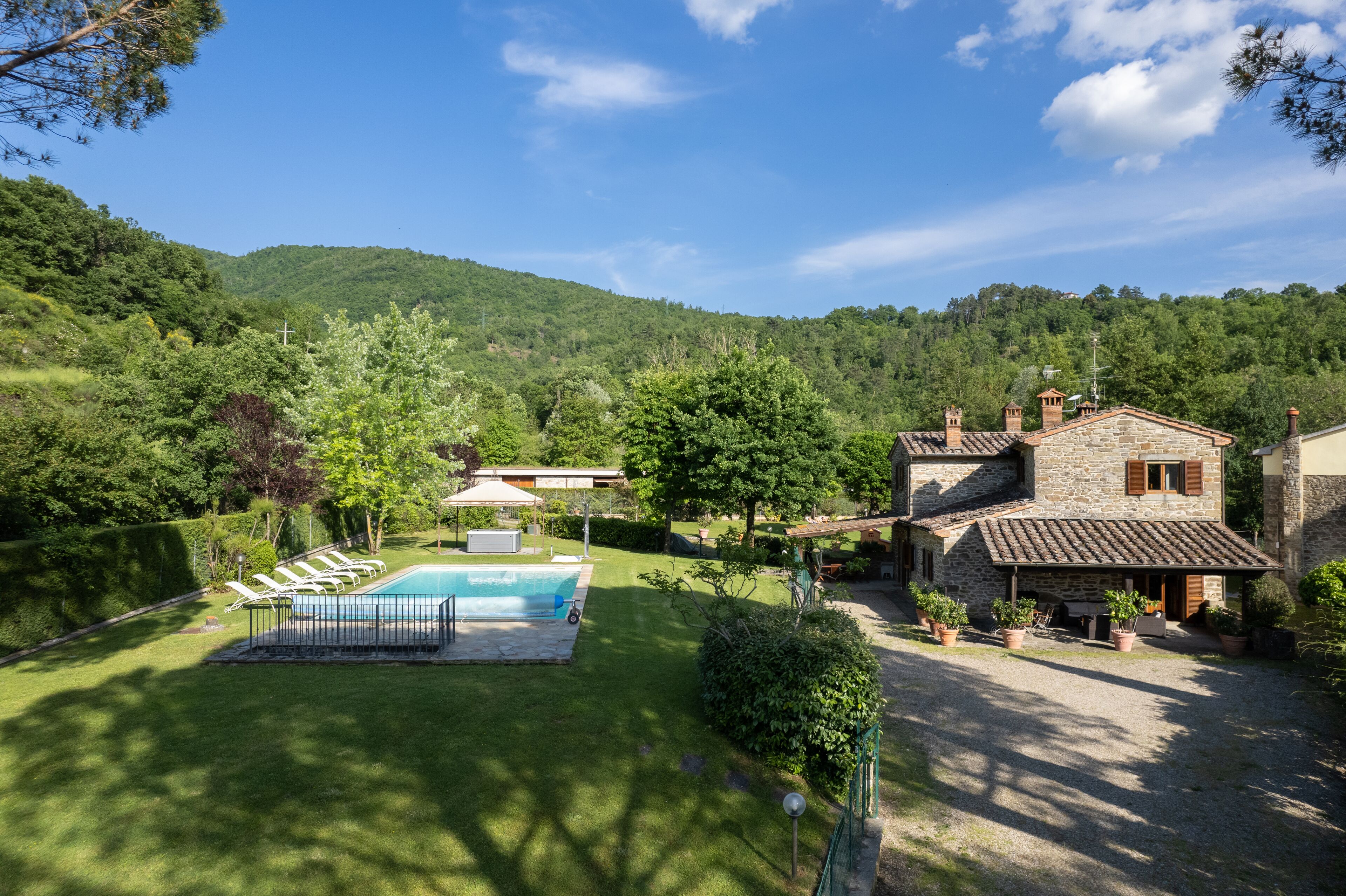 A house with a swimming pool, surrounded by a well-maintained lawn and trees.