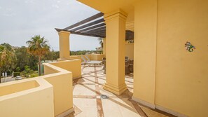 En solbeskinnet udendørs terrasse med havudsigt, med pergola, liggestole og fliset gulv.