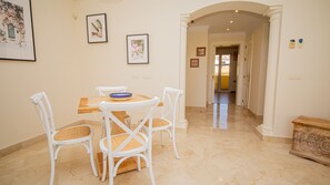 A dining area with a round table, four white chairs, and a blue bowl.