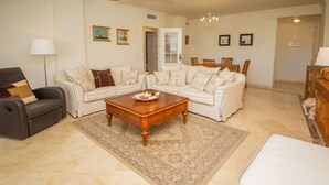 A living room with a sofa set, a coffee table, a rug, and a dining area with chairs and a table. - Terrazas de los Hidalgos F21A (Manilva)