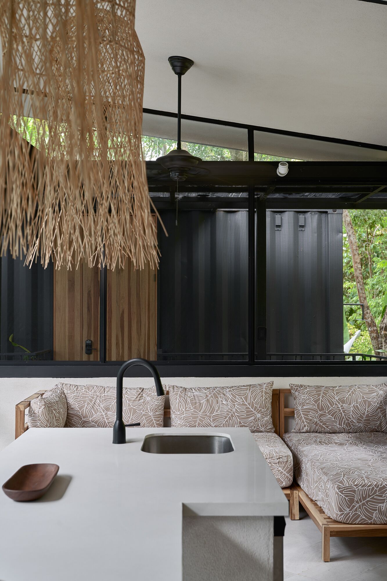 A modern kitchen with a white countertop, a black faucet, and a hanging light fixture.