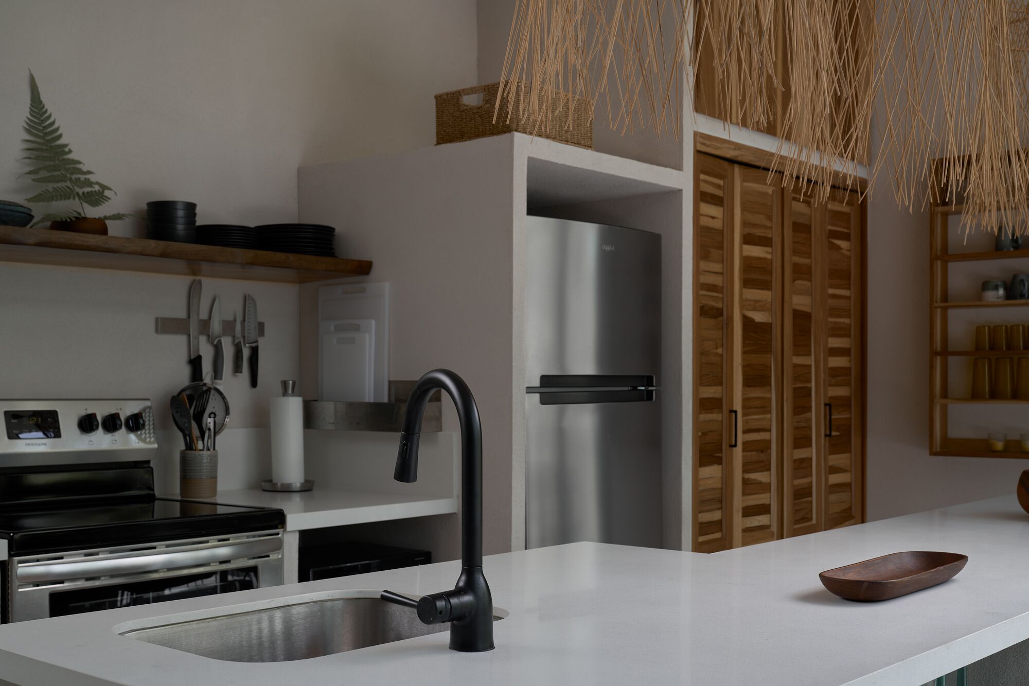 Una cocina moderna con un refrigerador de acero inoxidable, un grifo negro y un armario de madera.