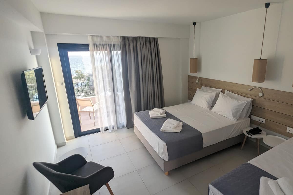 A hotel room with a bed, a chair, a small table, and a TV.
