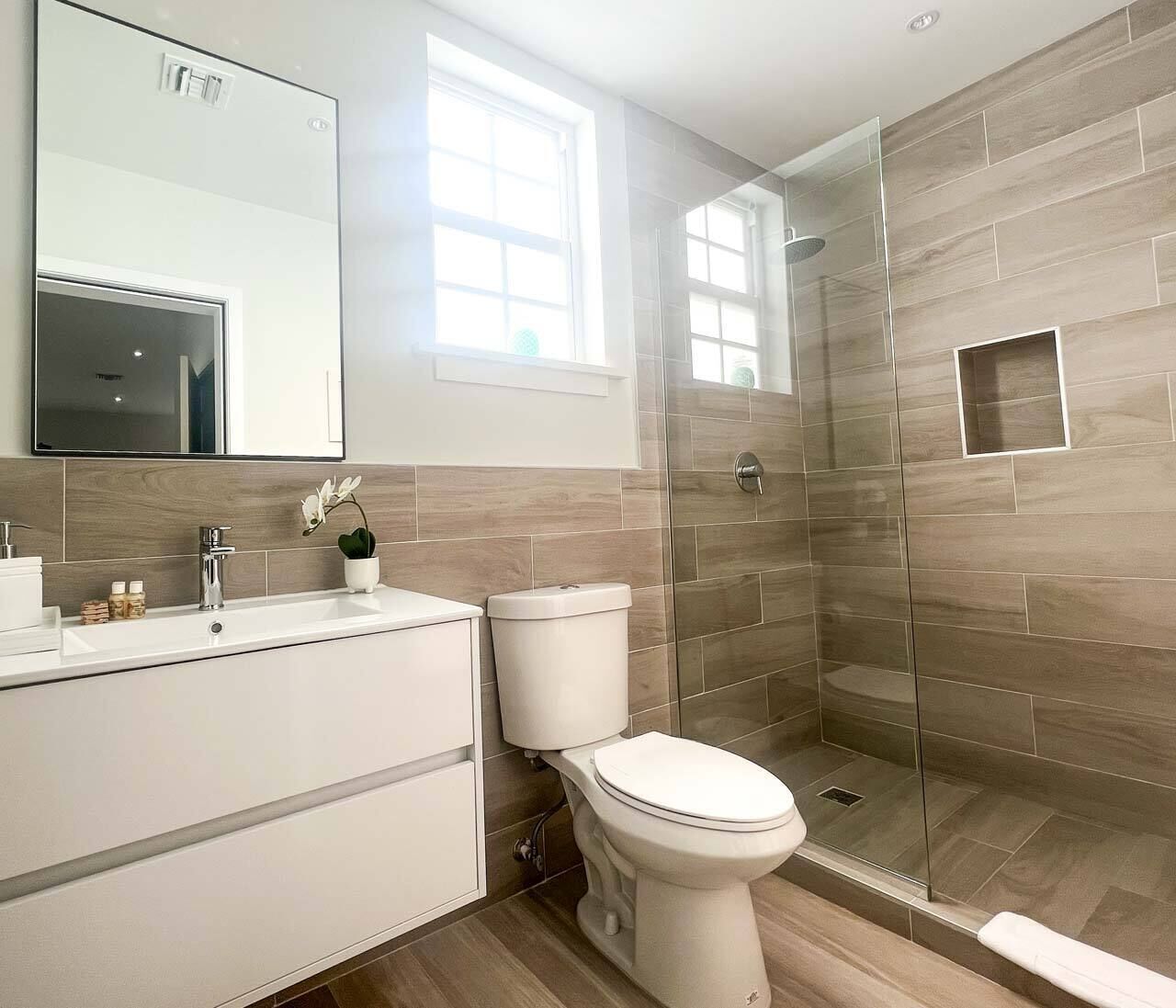 A modern bathroom with a shower, toilet, and sink.