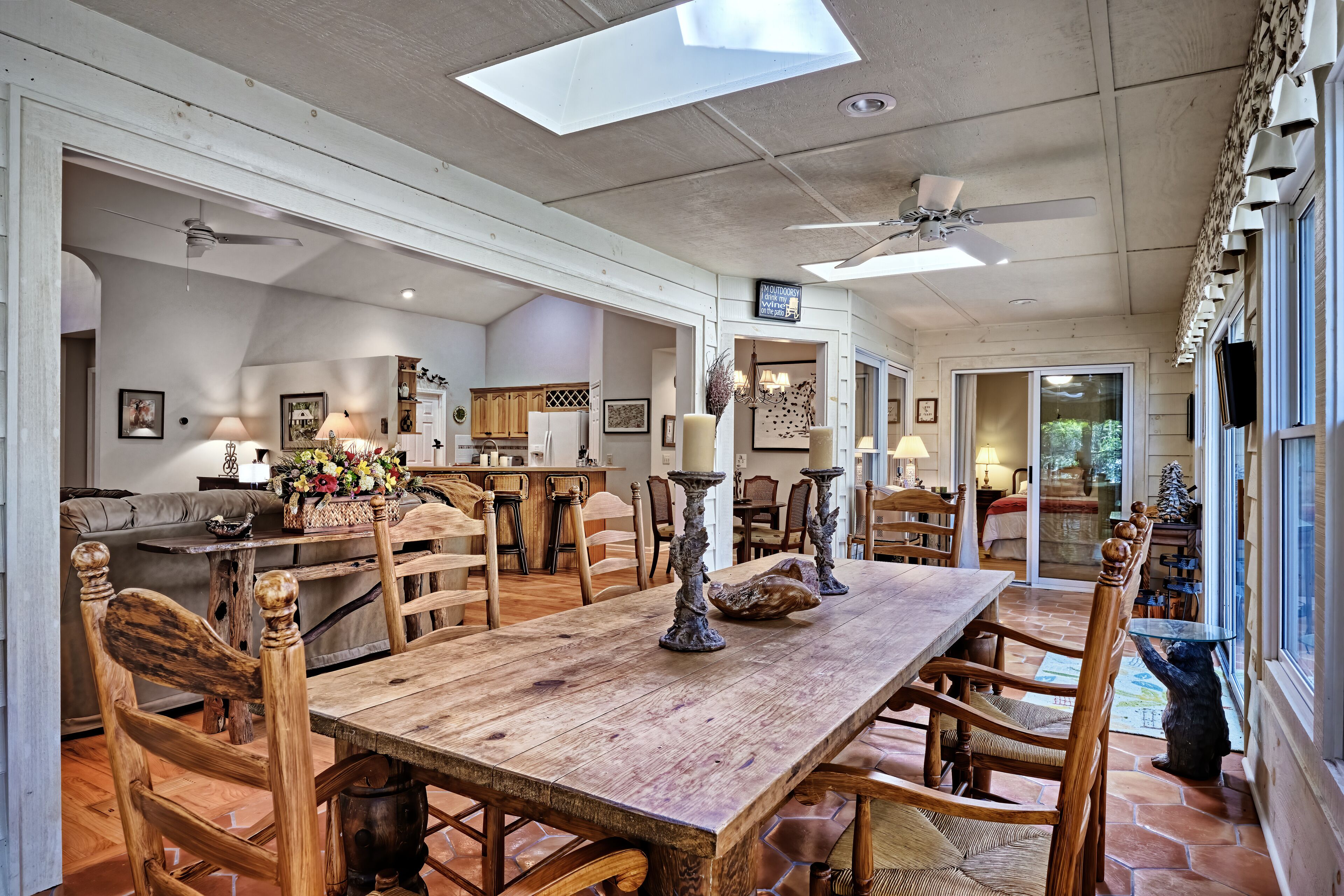 A spacious dining area with a rustic wooden table, multiple chairs, and a ceiling fan.