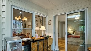 Un espacio habitable compacto con kitchenette, comedor y dormitorio con puerta corrediza a un patio.