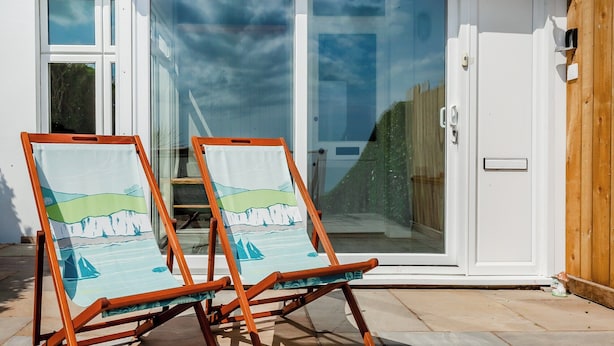 Two beach-themed lounge chairs outside a building with a glass door. - Stunning views of the English Channel and Brighton Marina. (Brighton)
