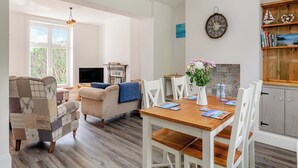 A cozy living room with a fireplace, a dining area with a wooden table and chairs, and a kitchen with wooden cabinets. - Stunning views of the English Channel and Brighton Marina. (Brighton)