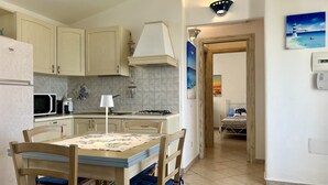 A compact kitchen with a dining area, a microwave, a stove, and a sink.