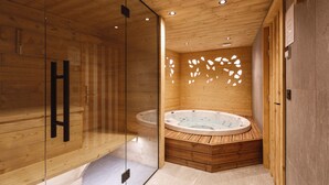 Eine Holzhütte mit einer gläsernen Dusche, einer Holzwanne und einer Holzwand mit ausgestanzten Mustern.
