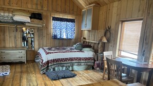 Een gezellig chalet-achtig vertrek met een bed, een houten tafel, een stoel en een bureau.