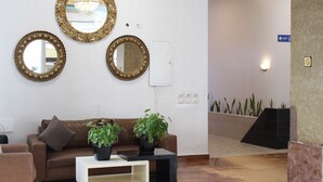 A reception area with a brown leather sofa, two potted plants, and three ornate mirrors on the wall. - Hotel Belle Vie (Kinshasa)