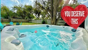 Ein Whirlpool mit einem herzförmigen Schild mit der Aufschrift „DAS HAST DU DIR ERWORTSCHAFT“ und einer Person im Wasser.