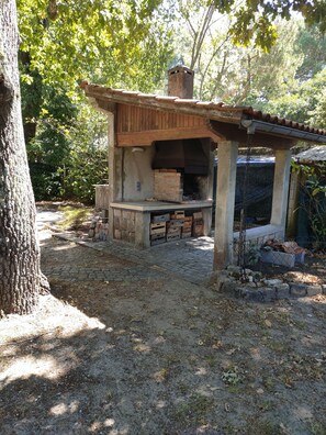 An outdoor brick oven structure with a chimney, surrounded by trees and a cobblestone path. - Villa Spacieuse, de Plain Pied, Avec Grand Jardin Arboré à 2 Minutes de la Plage (Andernos-les-Bains)