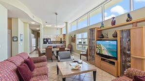 A spacious living area with a large TV, comfortable seating, and a view of the ocean. - Beautiful Gulf View, Private Beach Access, Fitness Room (Siesta Key)