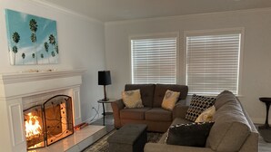 Ein Wohnzimmer mit Kamin, einer Couch, einem Teppich und einem Gemälde an der Wand.