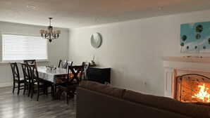Ein Wohnzimmer mit Kamin, eine Essecke mit Tisch und Stühlen sowie ein Sofa.