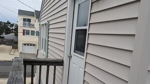 Um deck de madeira com uma porta e uma caixa de correio numa casa.