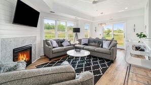 Un salon moderne avec une cheminée, deux canapés, une table basse et un téléviseur fixé au mur.