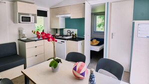 A compact room with a kitchenette, a dining area with a table and chairs, a small bed, and a window. - Relais du Léman (Messery)