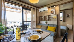 A dining area with a table set for four, a sofa with cushions, and a view of the outdoors. - Relais du Léman (Messery)