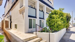 A modern building with a stone staircase leading to a white entrance, a large green bush, and a clear sky. - Newport Beach Vacation Rental Near Beach & Pier (Newport Beach)