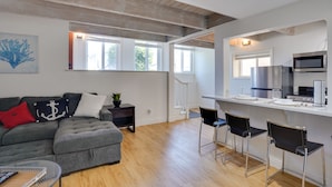 A modern living room with a grey sofa, a coffee table, and a dining area with bar stools. - Newport Beach Vacation Rental Near Beach & Pier (Newport Beach)