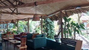 A covered outdoor seating area with wooden furniture and potted plants. - Green Garden Guest House  (Arusha)