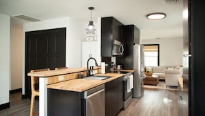 A modern kitchen with a wooden island, stainless steel appliances, and a black cabinet.