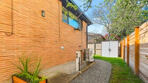 A brick building with a gravel pathway leading to a wooden fence. - Lilac in Law (Seattle)