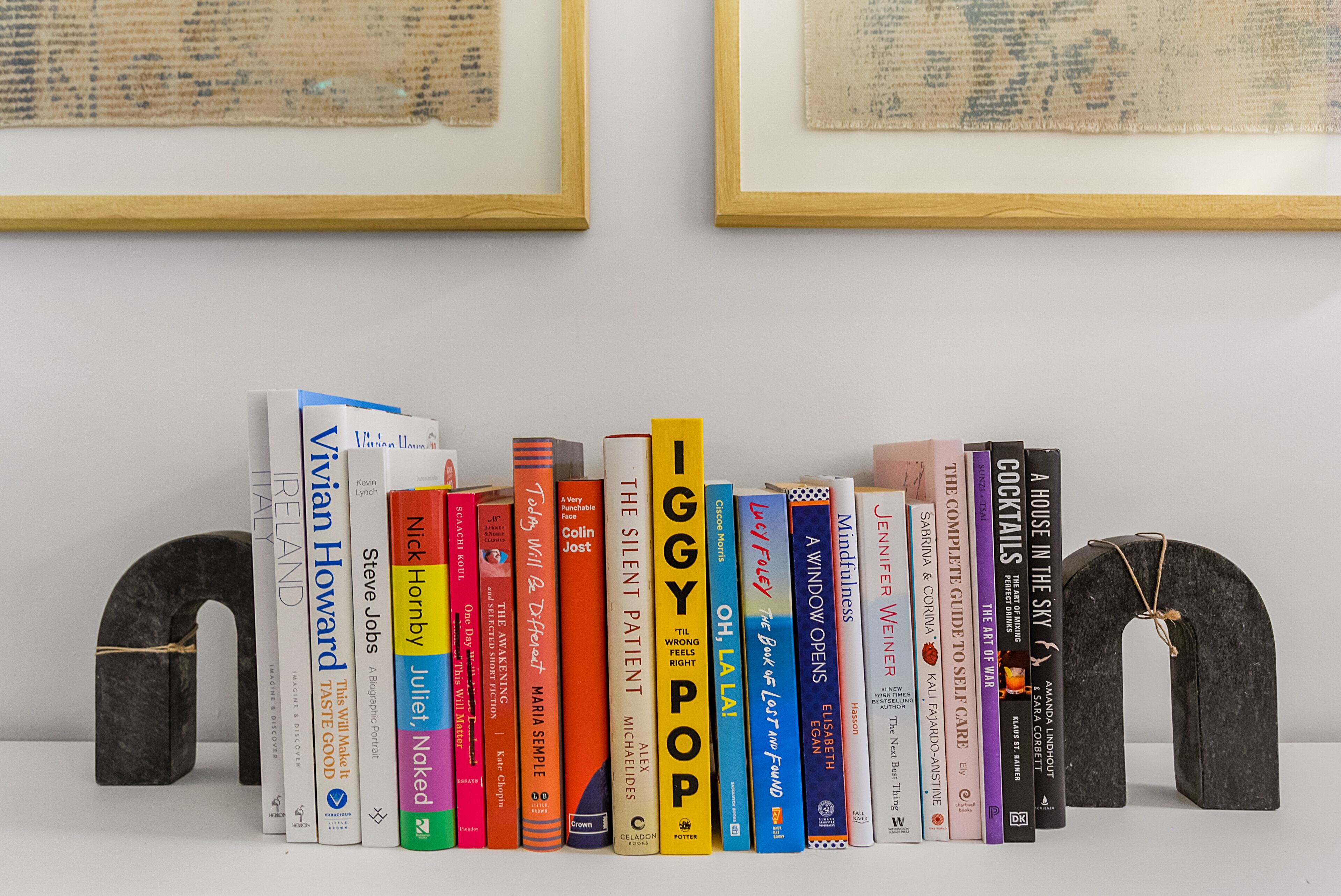 Una estantería con varios libros y dos estructuras decorativas de piedra.