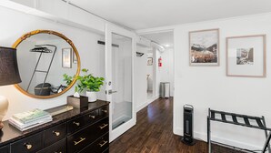 A hotel hallway with a mirror, a plant, a lamp, and framed pictures on the wall. - Lilac in Law (Seattle)