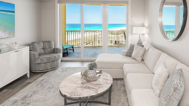 A living room with a white sofa, a patterned armchair, a marble coffee table, and a large mirror. - LAST Minute Cancellation! Luxurious gorgeous condo and includes beach service! (Panama City Beach)