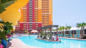 A hotel with a large pool, lounge chairs, and a tall building with balconies. - LAST Minute Cancellation! Luxurious gorgeous condo and includes beach service! (Panama City Beach)