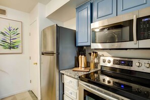 A modern kitchen with stainless steel appliances, including a refrigerator, microwave, and oven.