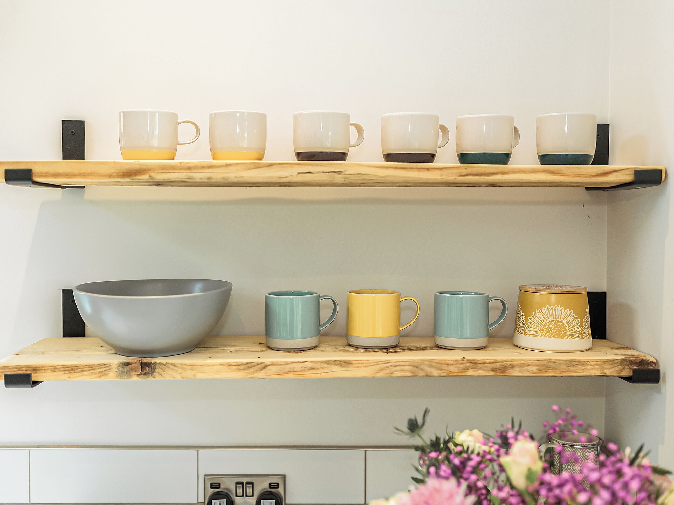 Une étagère de cuisine avec différentes tasses et un grand saladier.