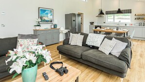 Una sala moderna con un sofá gris, una mesa de centro de madera y un jarrón con flores blancas.