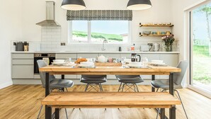 Una cocina moderna con una mesa de comedor de madera, sillas negras e iluminación colgante.
