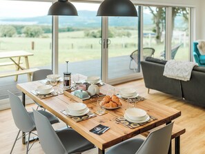 Een eettafel, gedekt met borden, glazen en een koffiepot, met uitzicht op een mooi landschap.
