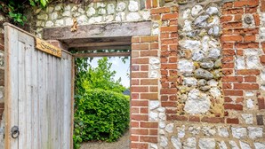 A wooden door with a sign, a stone wall, and a brick wall with vegetation growing on it. - 3 bedroom accommodation in South Creake, near Fakenham (South Creake, near Fakenham)