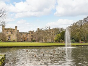A historic stone building with a large lawn and a fountain in the foreground. - 4 bedroom accommodation in Clitheroe (Clitheroe)